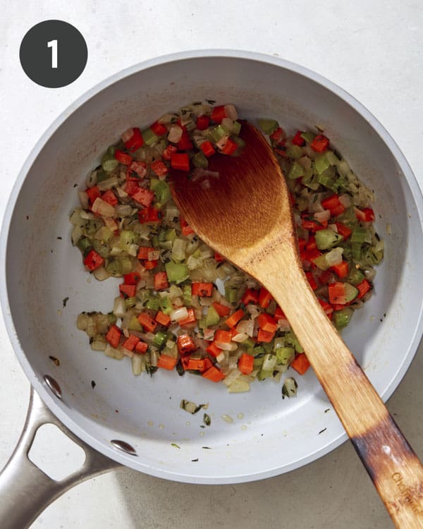 Carrots, celery, peas and onions cooking in a pot.