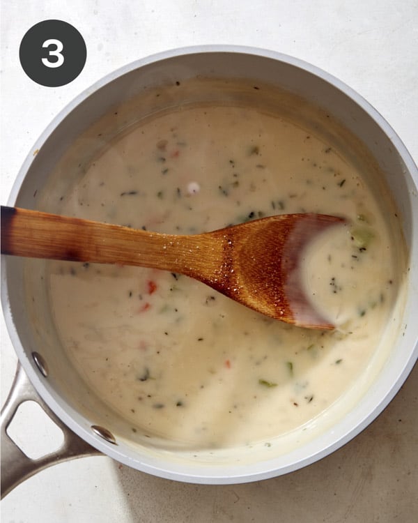 Chicken pot pie filling in a skillet cooking.