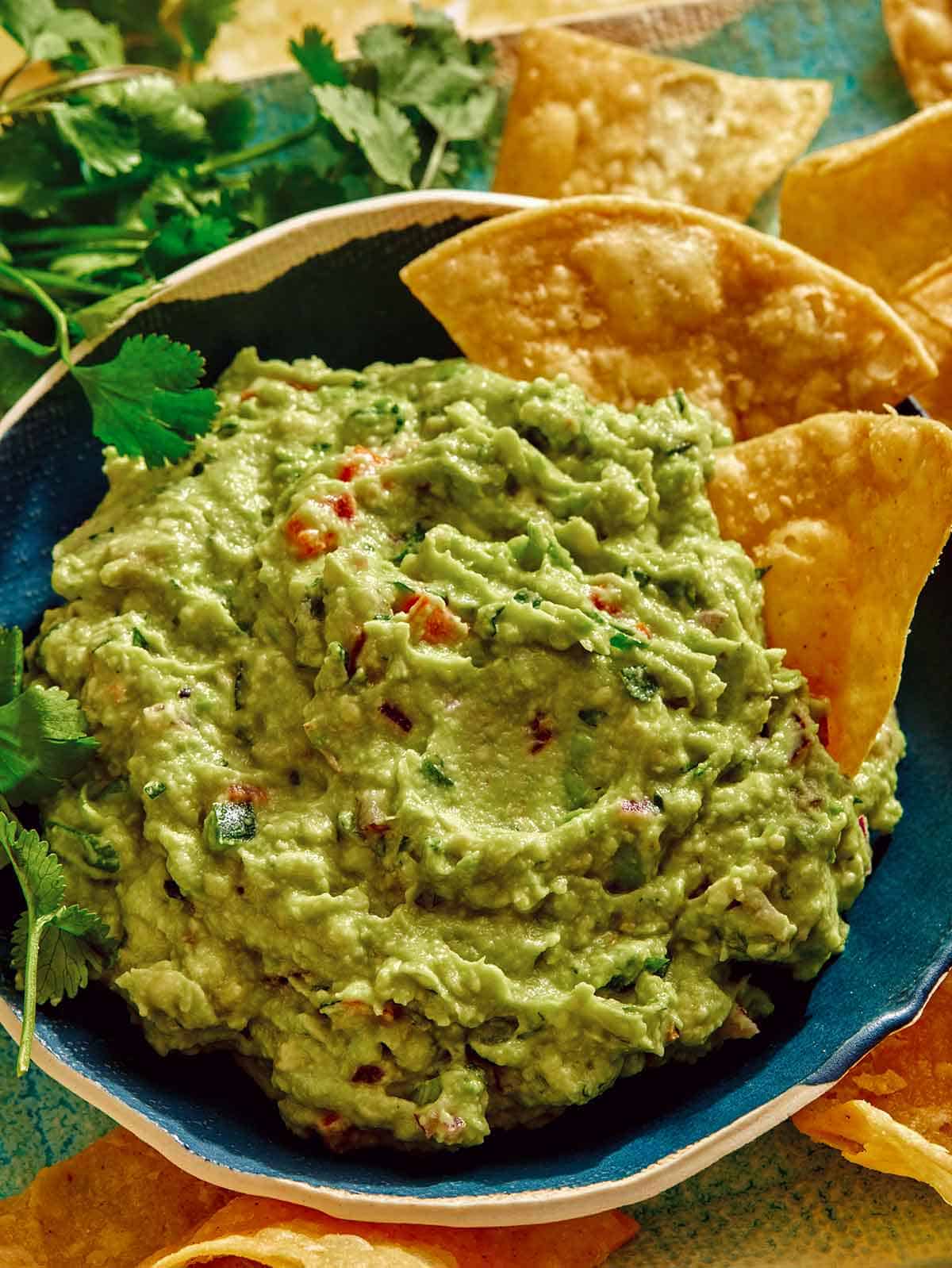Guacamole recipe in a bowl with chips on the side.