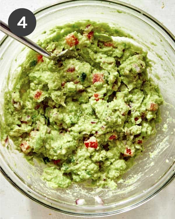Guacamole mashed in a glass bowl.