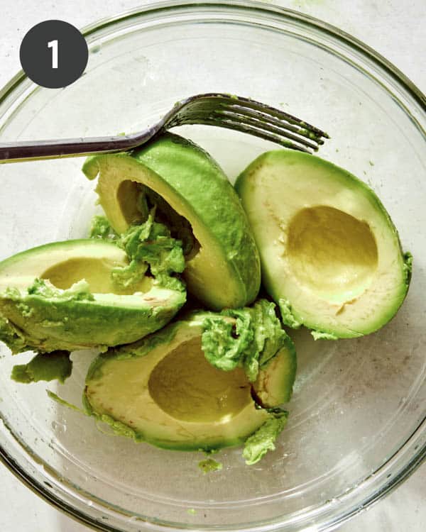 Avocados in a bowl about to mashed up.