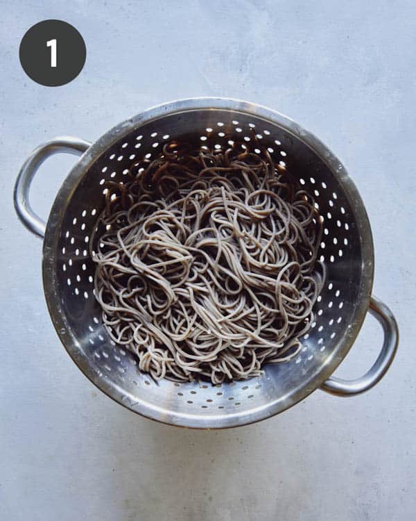 Boiled and drained soba noodles in a colander.
